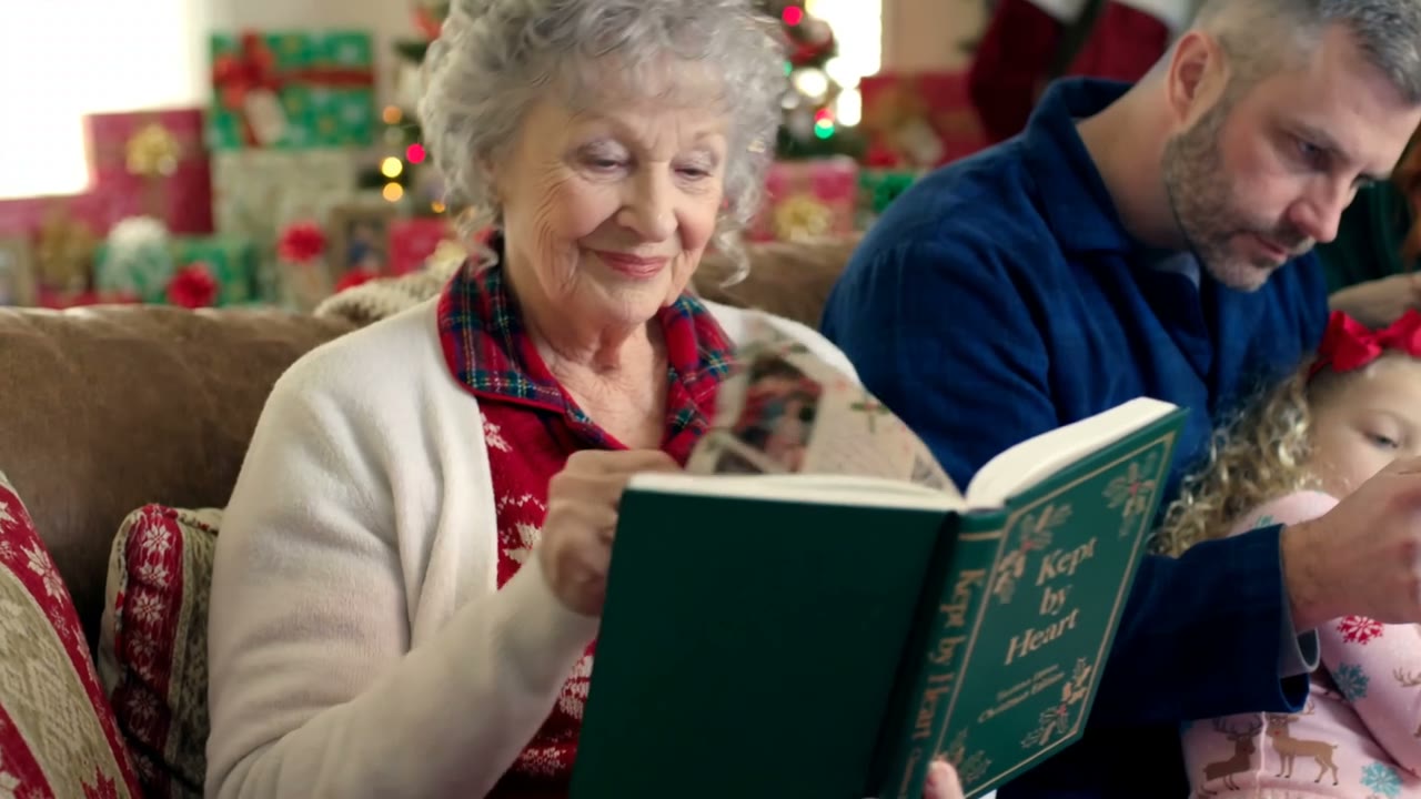 A grandmother holding her Kept by Heart book on Christmas morning, its green cover and gold title showing